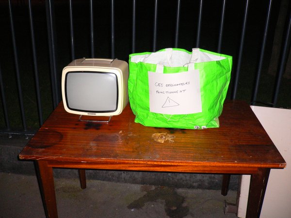 A côte de la télé, le sac avec le message 'Ces ordinateurs fonctionnent !'